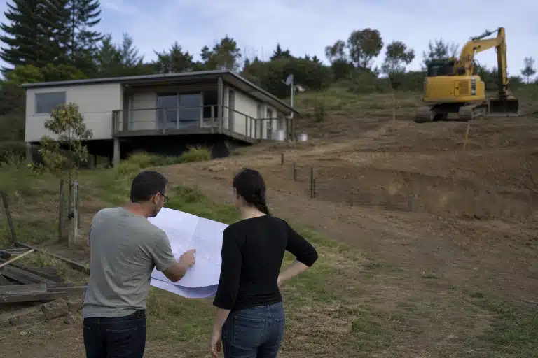 Deux personnes examinant des plans devant maison en travaux